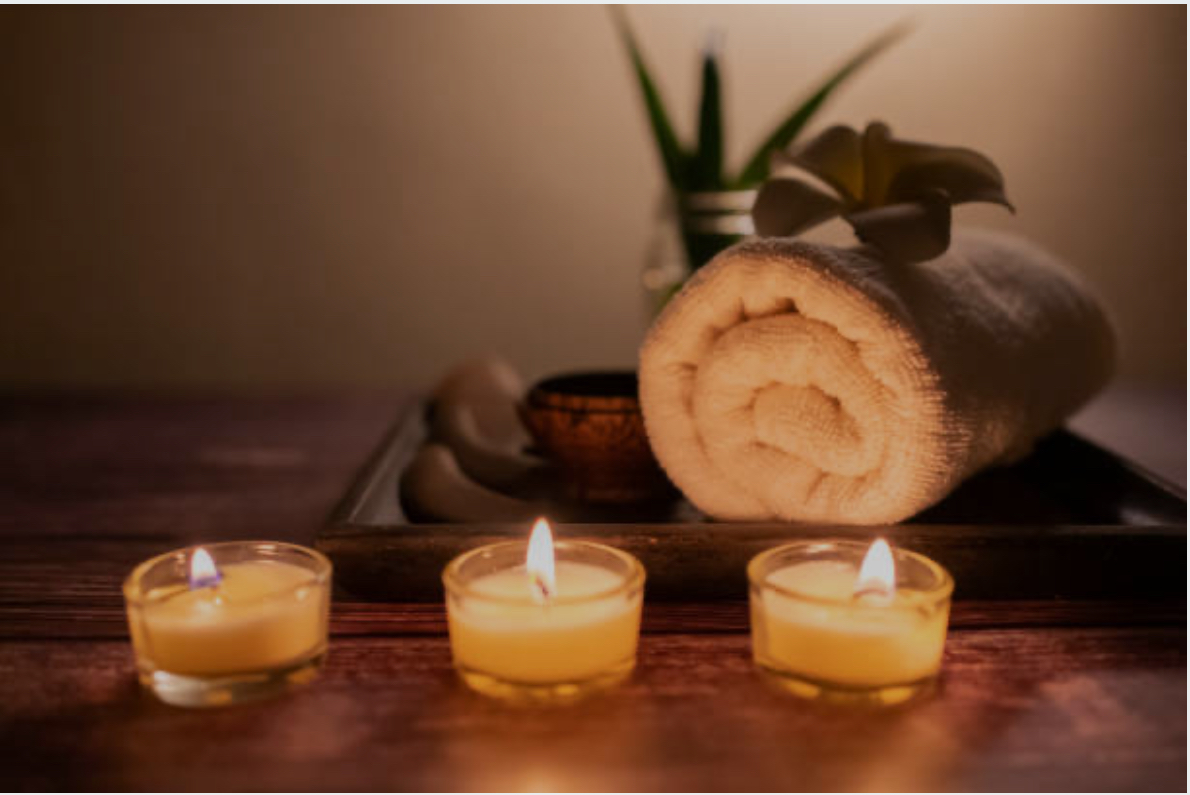 Soft candlelight with a rolled towel and spa details on a wooden surface.